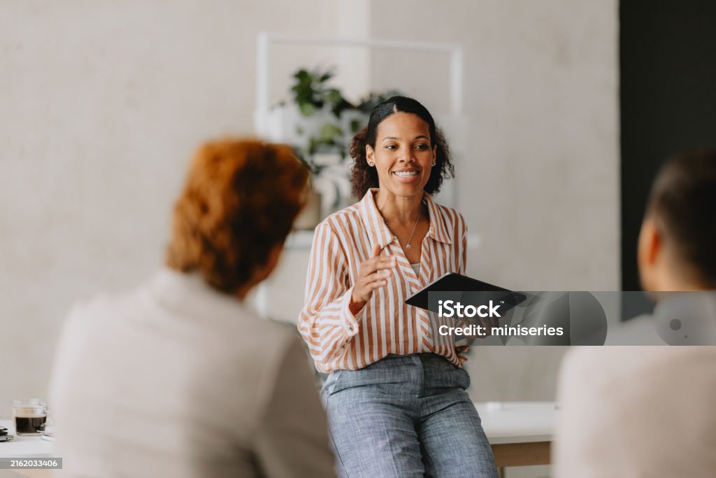 Reunión de negocios en oficina beige: mujer liderando equipo